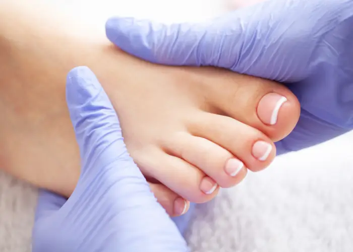 Gloved hands supporting a patient's foot after nail treatment
