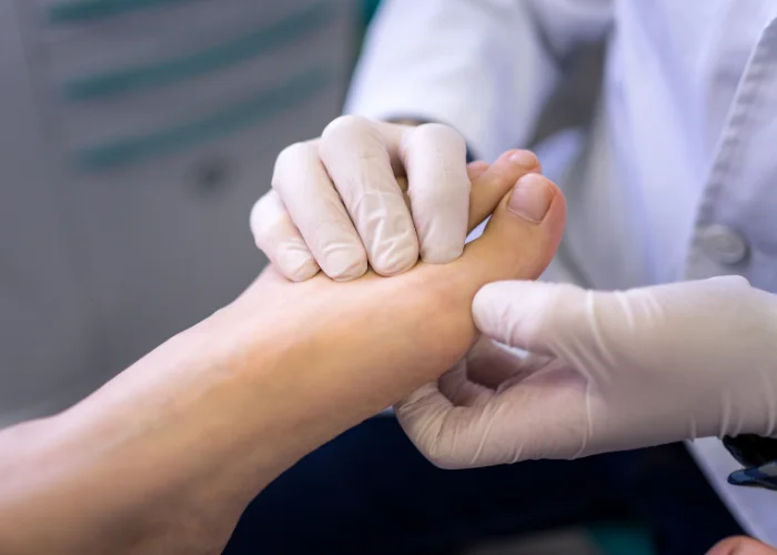 A gloved podiatrist examining the sole of a patient's foot