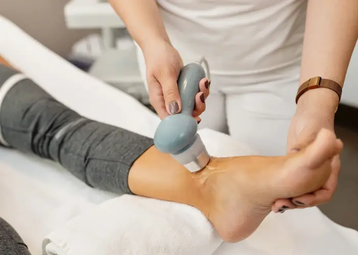 A clinician treating a patient's ankle with a handheld therapy device