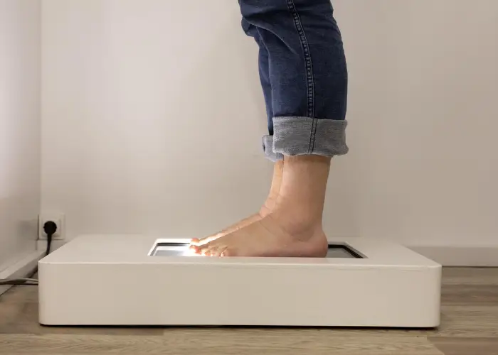 A bare foot standing on a 3D foot scanner used to design custom orthotics
